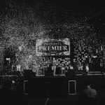 Apresentação musical em preto e branco com confetes caindo sobre o palco durante um show.