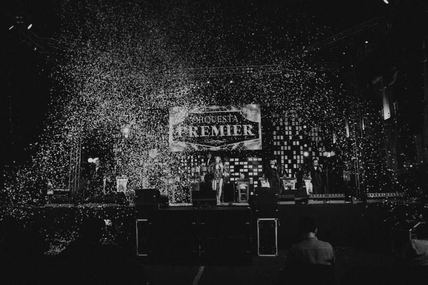 Apresentação musical em preto e branco com confetes caindo sobre o palco durante um show.