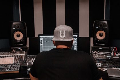 Produtor musical trabalha em um estúdio cercado por equipamentos de áudio.