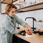 Mulher prepara vegetais frescos em uma cozinha.