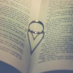 Livro aberto com alianças e elementos em formato de coração, em uma composição sobre amor e casamento